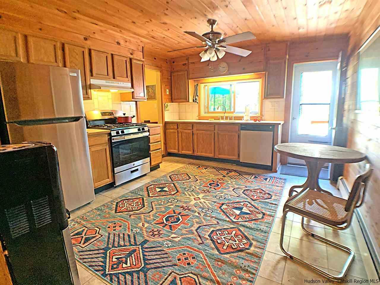 56 Bellwood Road Saugerties, NY 12477 - Photo 8 of 35 a kitchen with stainless steel appliances kitchen island granite countertop a sink a stove a dining table and chairs with wooden floor