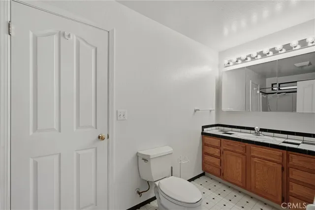 a bathroom with a granite countertop toilet and a sink