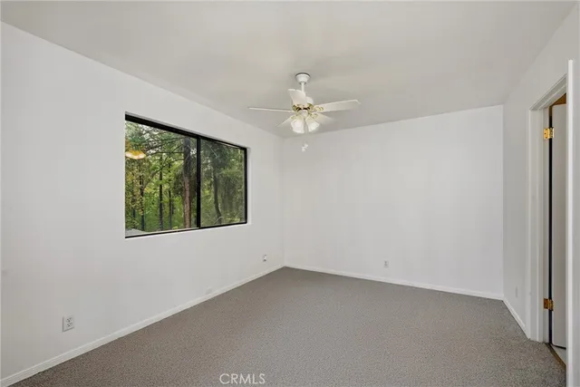 an empty room with a window and a fan