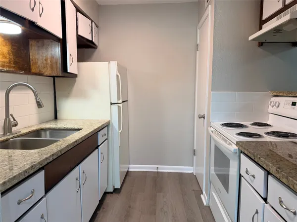 a kitchen with granite countertop a sink stove and refrigerator