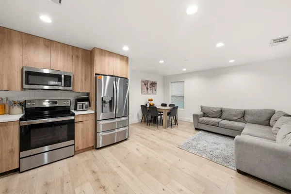 a living room with furniture a flat screen tv and kitchen view