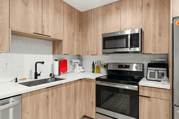 a kitchen with granite countertop a sink dishwasher stove and microwave with wooden cabinets