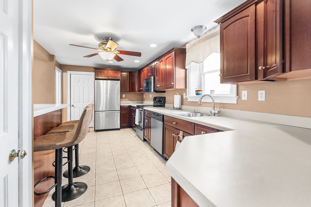 41 Pilgrim Road Weymouth, MA 02191 - Photo 2 of 27 a kitchen with stainless steel appliances granite countertop a sink a stove top oven a chimney cabinets and a dining table
