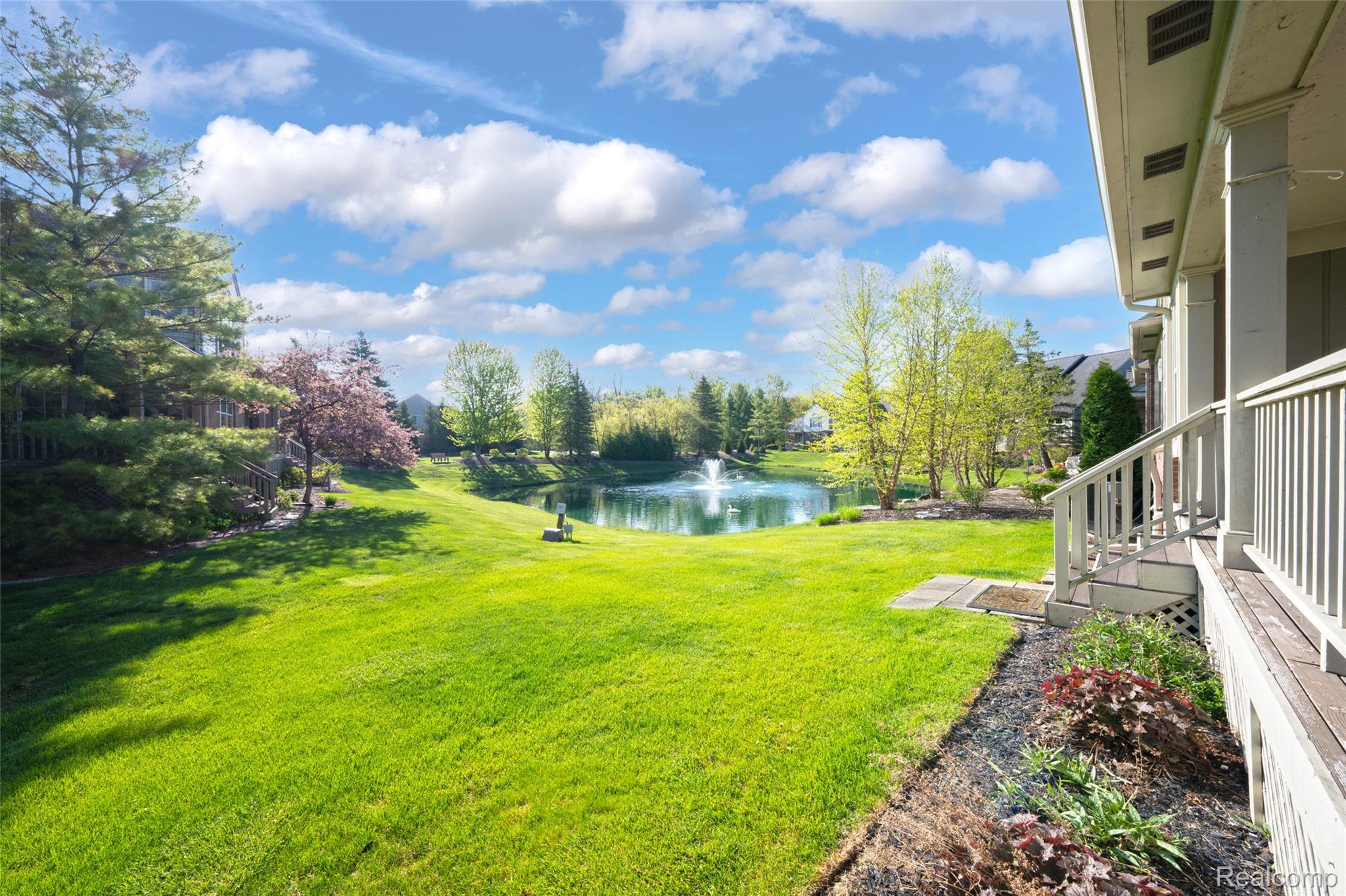 3805 Windingbrook Circle, Unit 22 Rochester, MI 48309 - Photo 59 of 63 Expansive backyard featuring a manicured lawn, a tranquil pond with a fountain, and mature landscaping