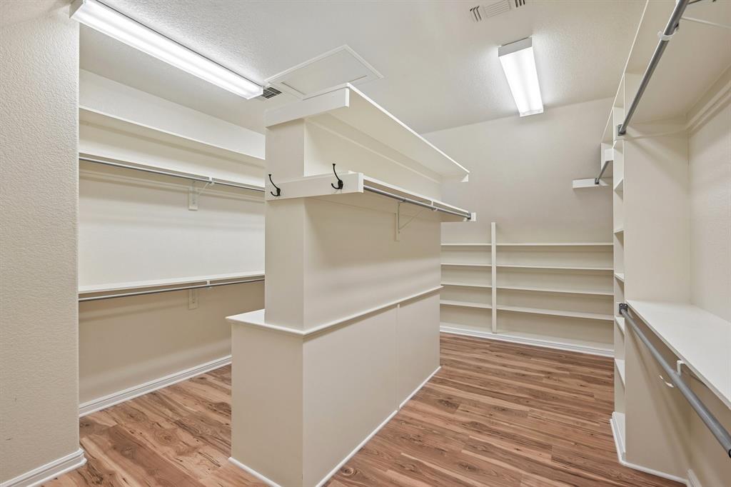 2085 Switzer Road Sanger, TX 76266 - Photo 20 of 39 Spacious walk-in closet featuring wood-finish flooring, extensive shelving, multiple hanging rods, and a central built-in island with additional storage and integrated hooks