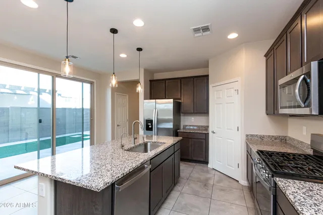 a kitchen with granite countertop a sink a counter top space appliances and cabinets