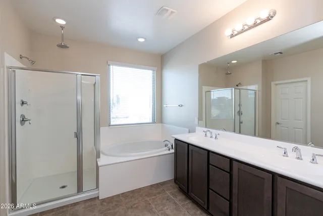 a bathroom with a tub double sink shower and mirror