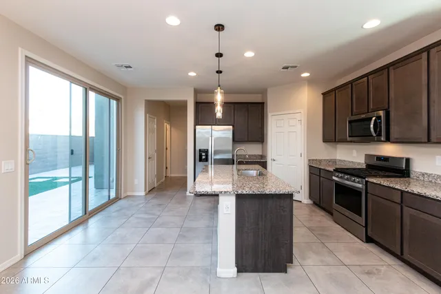 a large kitchen with stainless steel appliances granite countertop a stove refrigerator and a view of living room