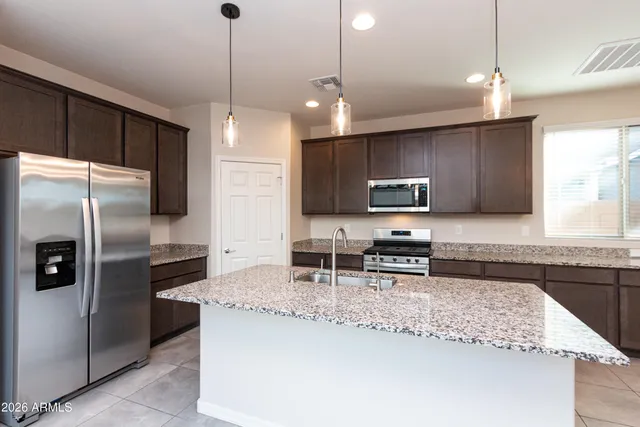 a kitchen with stainless steel appliances granite countertop a refrigerator a sink a stove a microwave and wooden cabinets