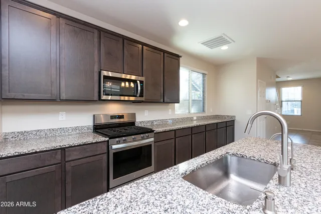 a kitchen with stainless steel appliances granite countertop a sink a stove a microwave and cabinets