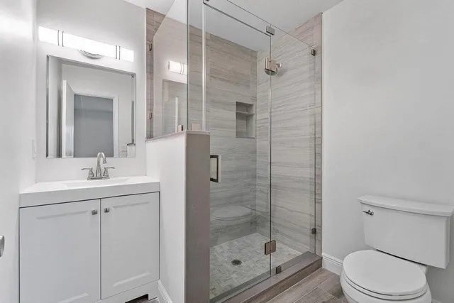 a bathroom with a shower a sink a toilet and mirror