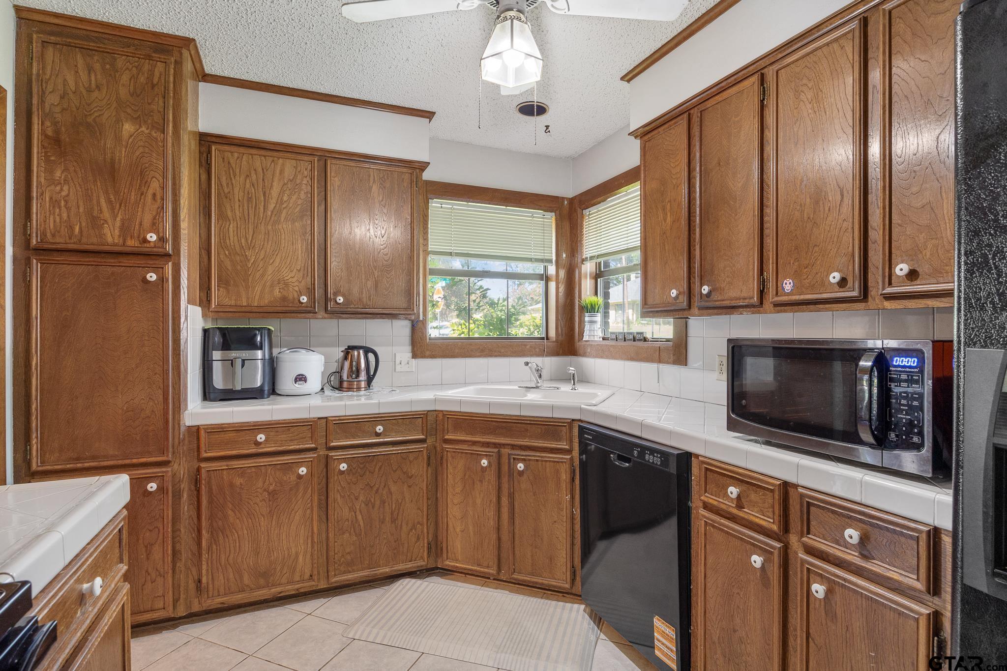 802 Carriage Drive Tyler, TX 75703 - Photo 7 of 21 a kitchen with a sink dishwasher a stove and a microwave oven