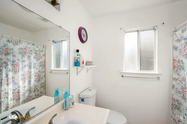 a bathroom with a sink a toilet and shower curtain