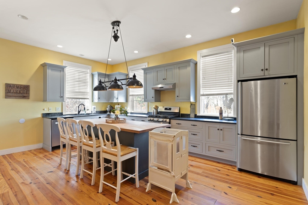 22 Sanderson Road Littleton, MA 01460 - Photo 12 of 30 a kitchen with a dining table chairs stainless steel appliances and cabinets