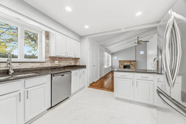 a kitchen with granite countertop a sink and white cabinets