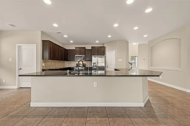 a large kitchen with granite countertop a large counter top and stainless steel appliances