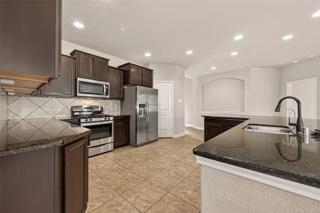 a kitchen with kitchen island stainless steel appliances a sink and a refrigerator