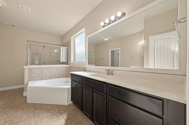 a bathroom with a bathtub a double vanity sink and a mirror