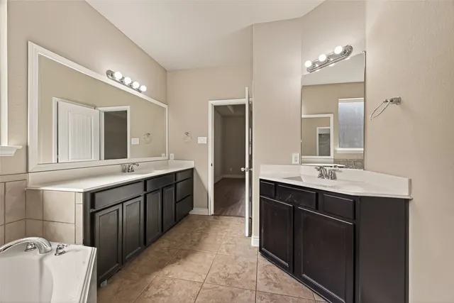 a spacious bathroom with a double vanity sink mirror and bathtub