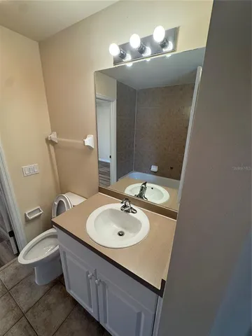 a view of an empty room with wooden floor and a chandelier fan