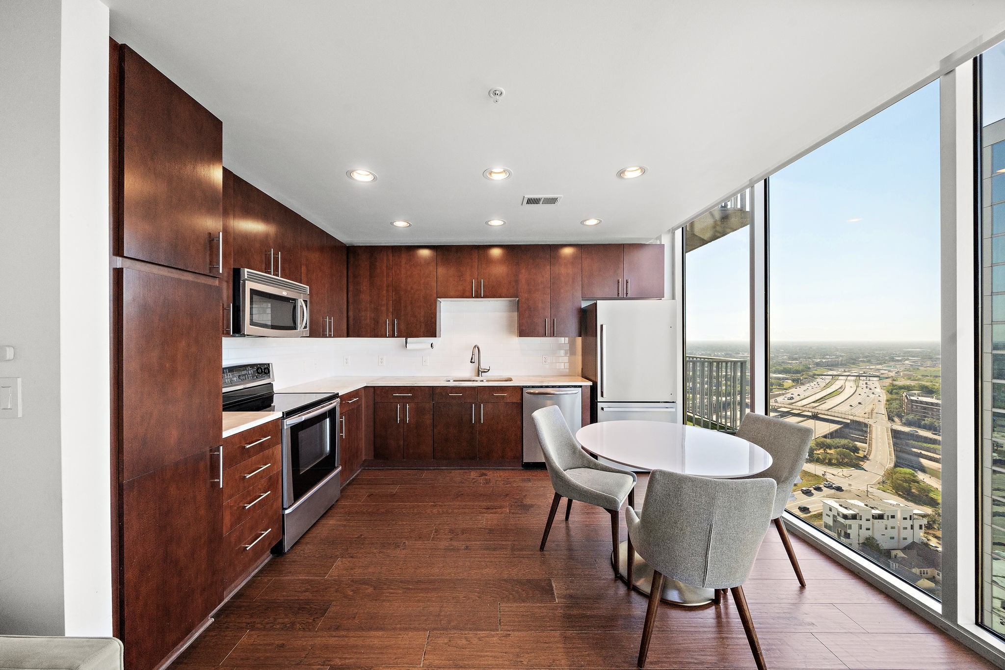 5925 Almeda Road, Unit 12312 Houston, TX 77004 - Photo 8 of 19 a kitchen with stainless steel appliances granite countertop a refrigerator a sink a stove a dining table and chairs with wooden floor