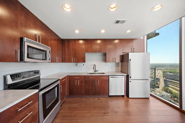a kitchen with a refrigerator a microwave oven and a sink with wooden floor