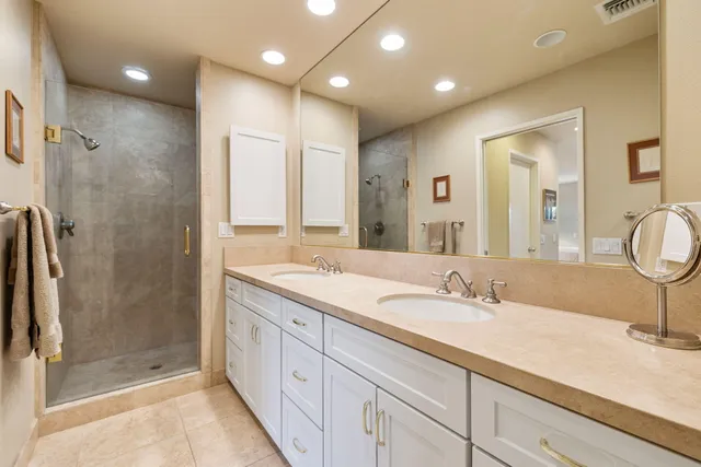 a bathroom with a double vanity sink mirror and shower