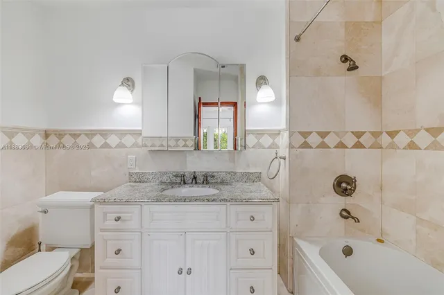 a bathroom with a granite countertop sink mirror and a bathtub