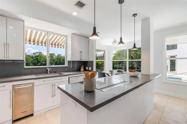 a kitchen with a sink a counter top space and living room view