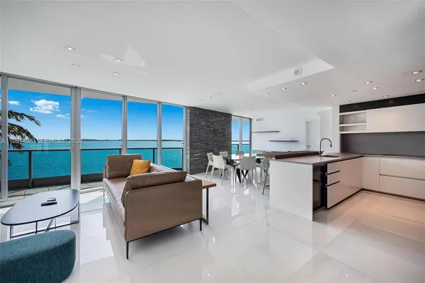 a living room with furniture a flat screen tv and a view of kitchen