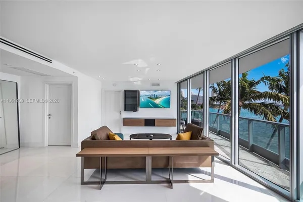 a living room with furniture a flat screen tv and a floor to ceiling window