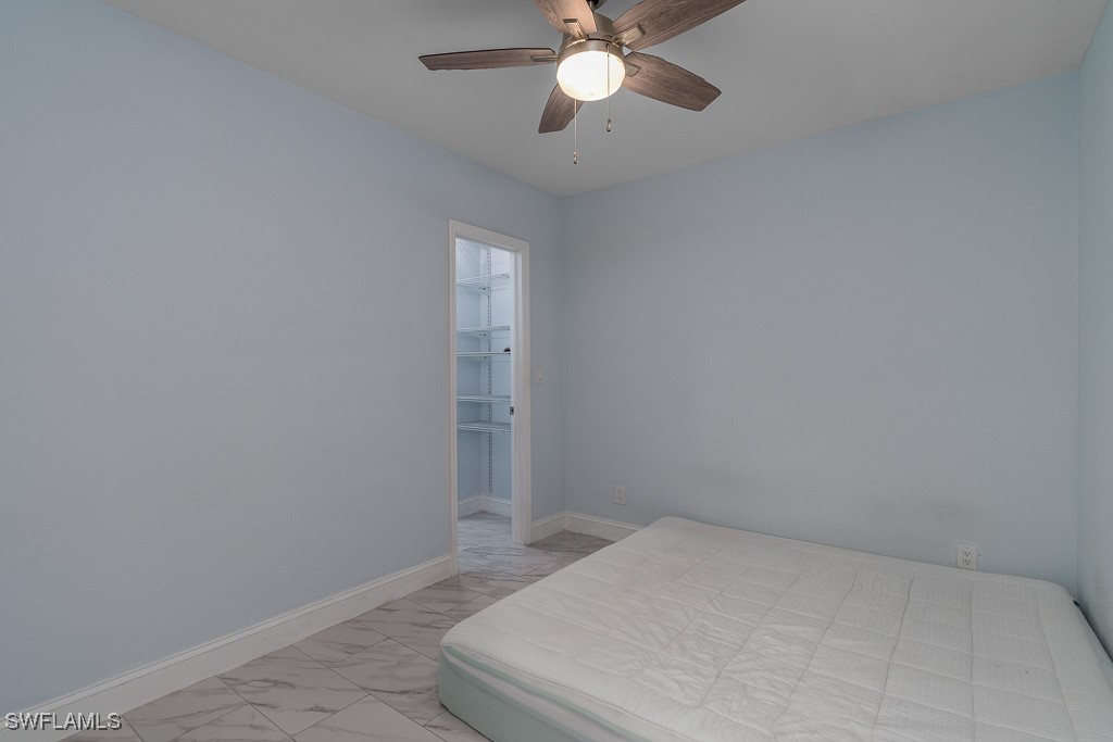 2808 9th Street Southwest Lehigh Acres, FL 33976 - Photo 17 of 34 a bedroom with a bed and a chandelier fan
