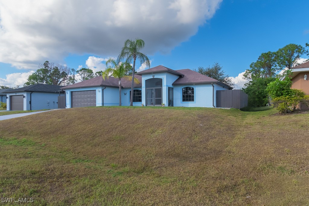 2808 9th Street Southwest Lehigh Acres, FL 33976 - Photo 24 of 34 a front view of a house with a garden and yard