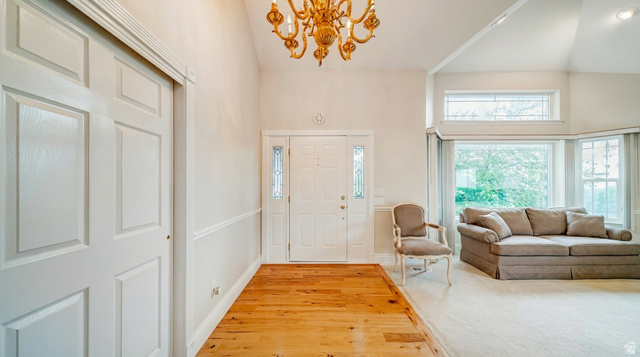1273 Grayson Court Sandy, UT 84094 - Photo 4 of 27 Foyer featuring hardwood flooring, a vaulted ceiling with an ornate chandelier, and a paneled entry door with sidelights