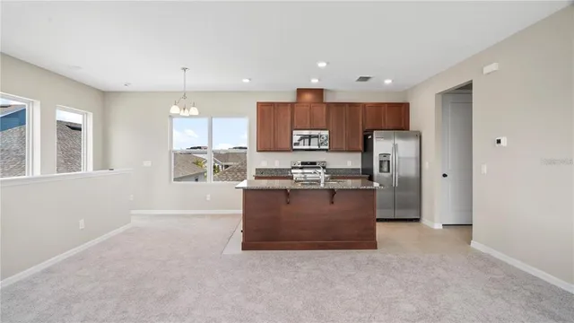 a large kitchen with stainless steel appliances kitchen island granite countertop a refrigerator and a stove top oven