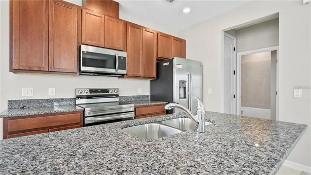 a kitchen with stainless steel appliances granite countertop a refrigerator stove and sink