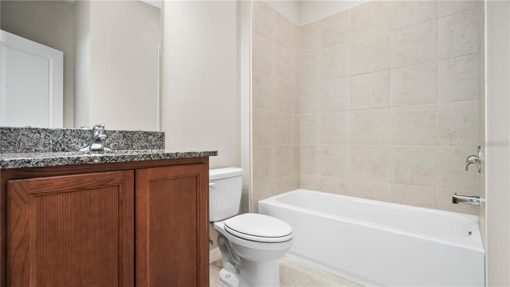3131 Voyager Avenue St. Cloud, FL 34771 - Photo 8 of 9 a bathroom with a granite countertop bathtub sink vanity mirror and toilet