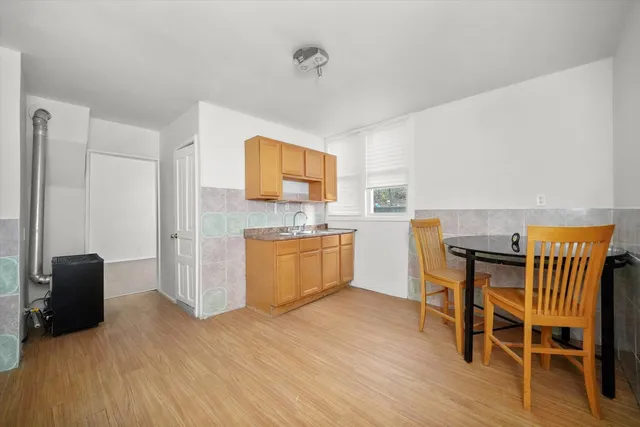 a kitchen with a table chairs wooden floors and a view of living room