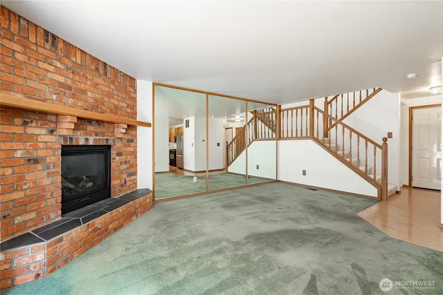 a view of an empty room with wooden floor fireplace and a window