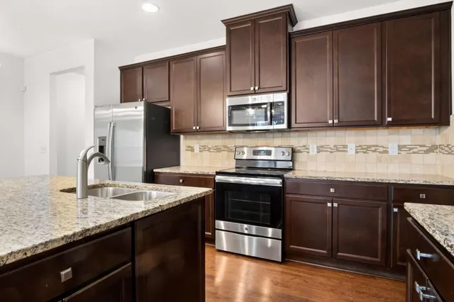a kitchen with stainless steel appliances granite countertop wooden cabinets a stove top oven a sink and dishwasher