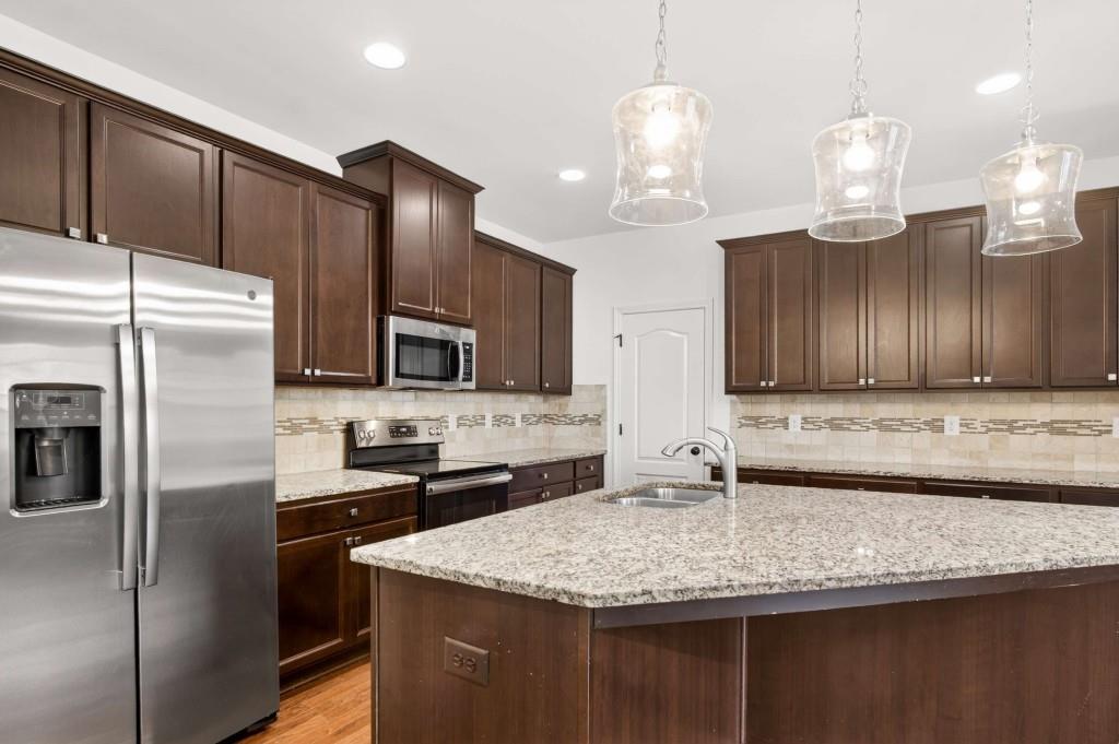 7631 Bucknell Terrace Fairburn, GA 30213 - Photo 13 of 43 a kitchen with kitchen island granite countertop stainless steel appliances a sink a refrigerator a stove and cabinets
