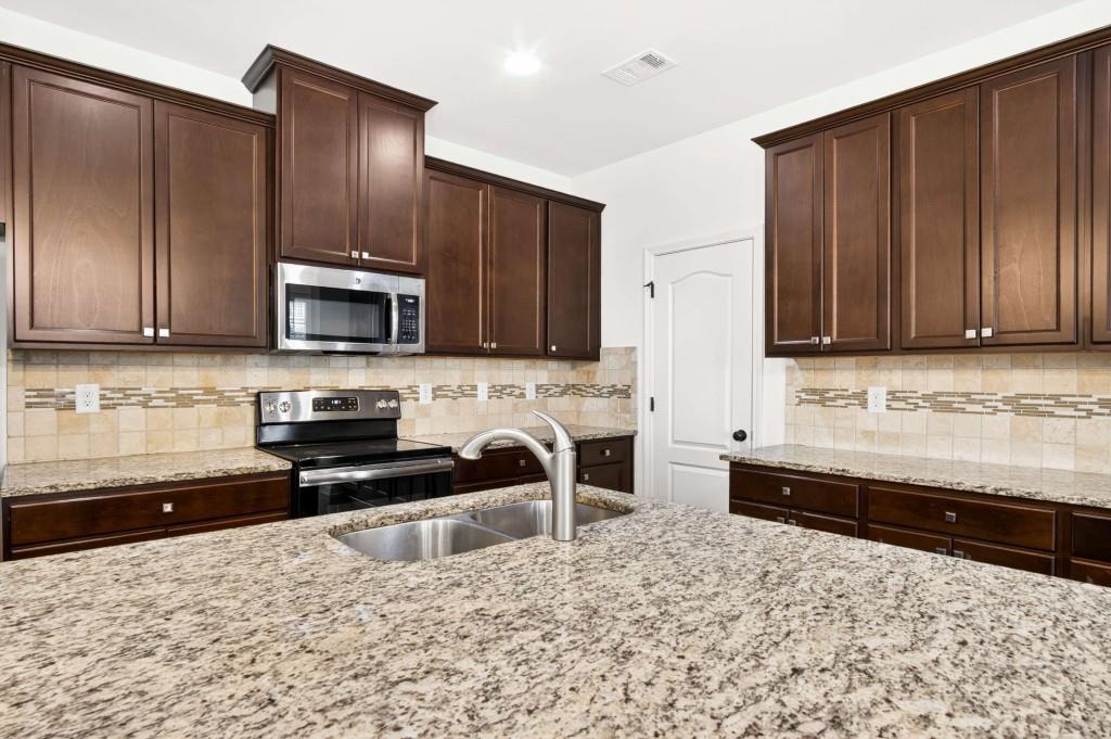 7631 Bucknell Terrace Fairburn, GA 30213 - Photo 15 of 43 a kitchen with stainless steel appliances granite countertop a stove a sink and a microwave