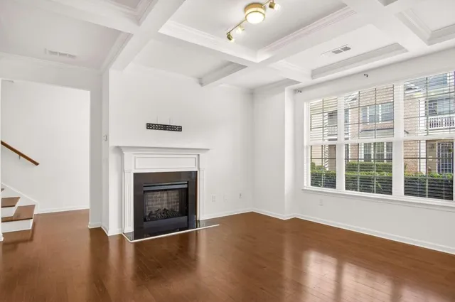 a view of an empty room with wooden floor fireplace and a window