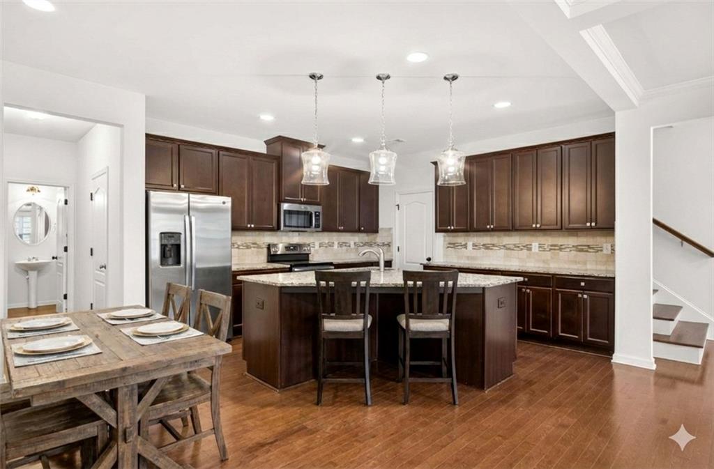 7631 Bucknell Terrace Fairburn, GA 30213 - Photo 8 of 43 a kitchen with stainless steel appliances kitchen island granite countertop a table chairs and a refrigerator
