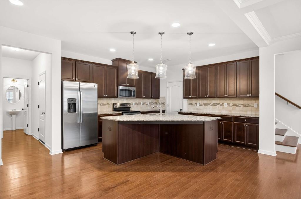 7631 Bucknell Terrace Fairburn, GA 30213 - Photo 9 of 43 a kitchen with stainless steel appliances granite countertop a refrigerator a sink dishwasher a stove and white cabinets with wooden floor