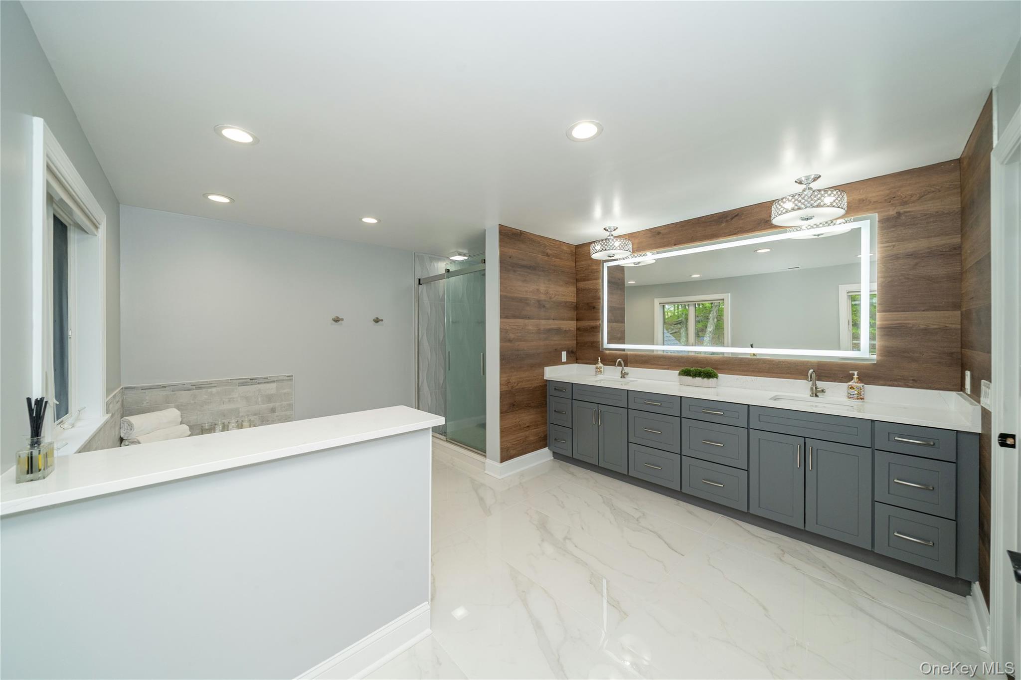 630 Chappaqua Road Briarcliff Manor, NY 10510 - Photo 29 of 41 Spa-like primary bathroom with double vanity, quartz countertops, soaking tub, oversized shower, and designer wood accent wall details