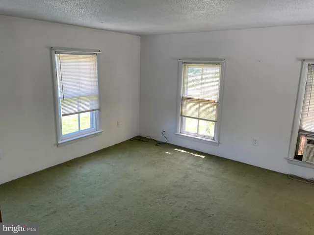 a view of a refrigerator in kitchen and an empty room