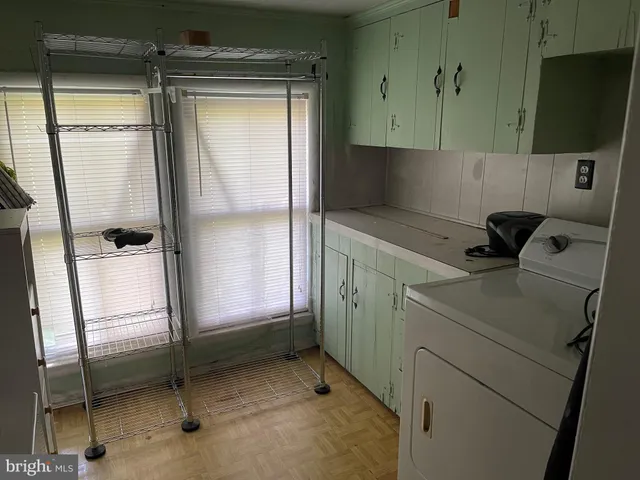 an empty room with wooden floor and windows with curtains