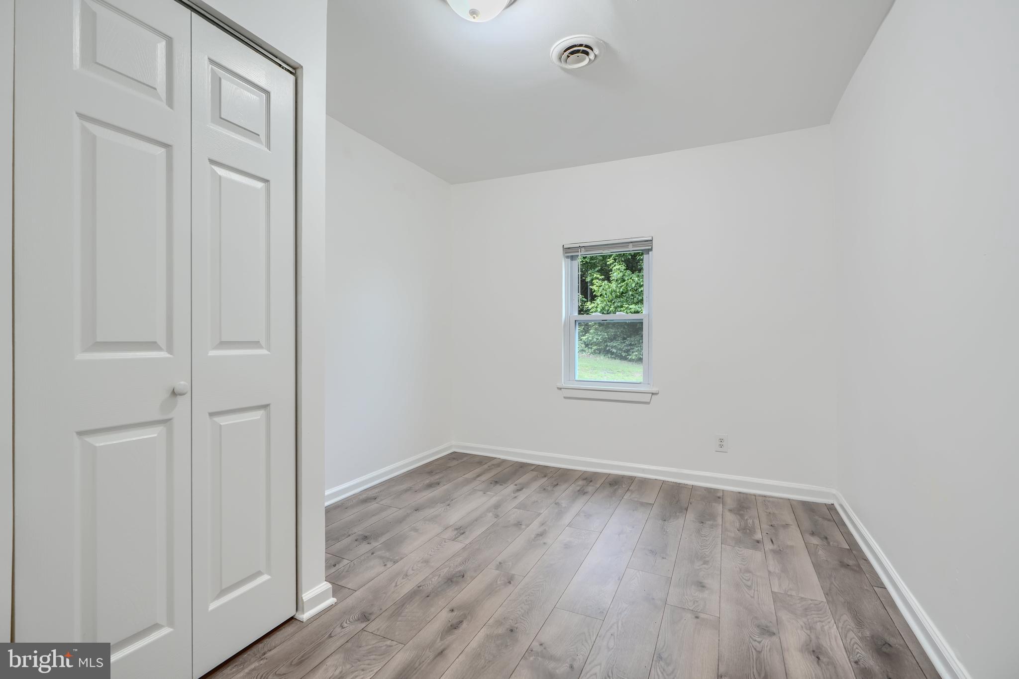 227 Elizabeth Avenue Baltimore, MD 21225 - Photo 15 of 31 an empty room with wooden floor and window