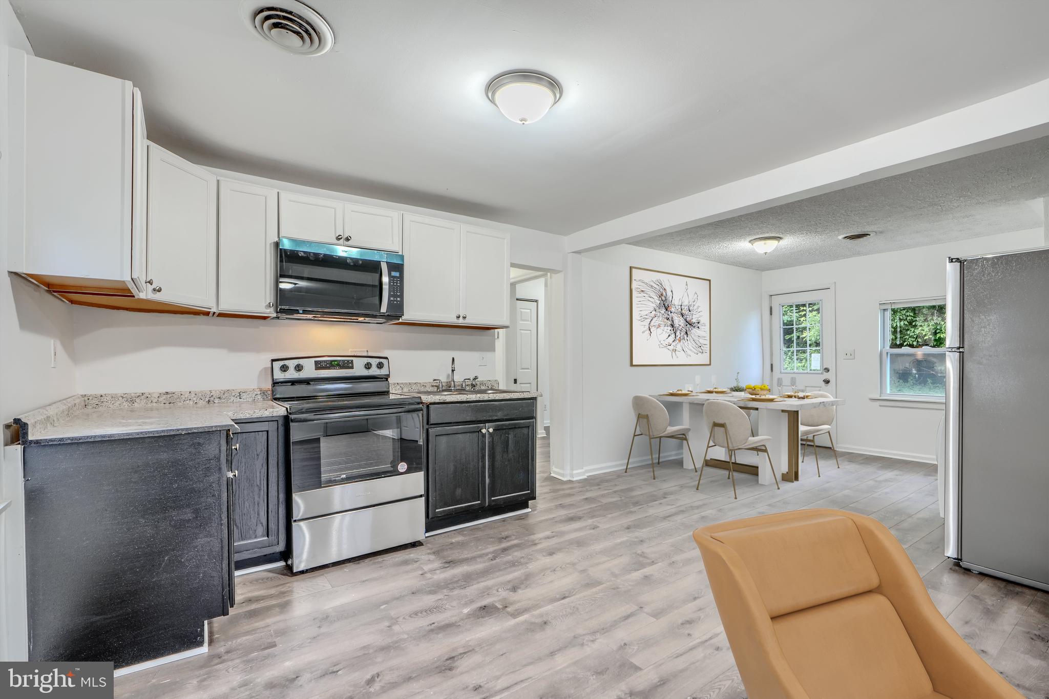227 Elizabeth Avenue Baltimore, MD 21225 - Photo 2 of 31 a kitchen with stainless steel appliances granite countertop a stove top oven a sink dishwasher a dining table and chairs with wooden floor
